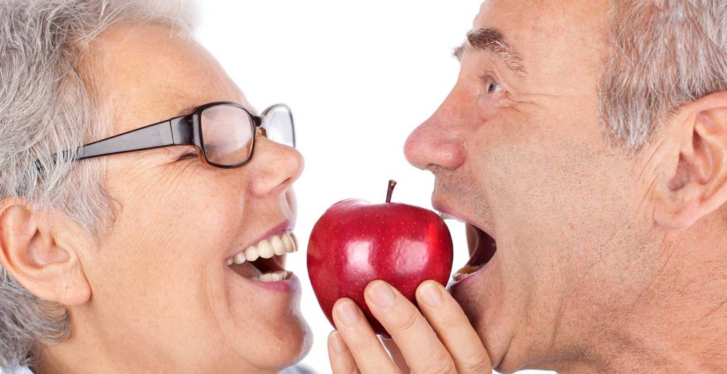 Couple biting an apple with dentures